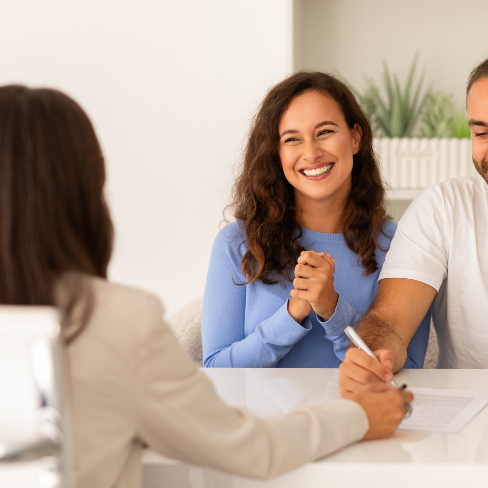 Delighted young couple singing papers at real estate agent office