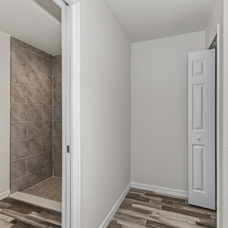 Bathroom hallway looking toward tiled walk-in shower, toilet, and vanity space