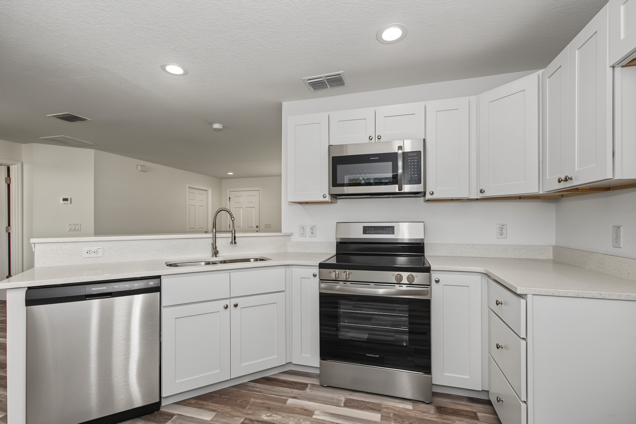 Kitchen design with white cabinetry, granite counter space, built-in microwave, and stainless steel stove.