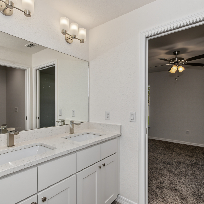 Modern bathroom double vanity with white cabinets, light granite countertops, and brushed nickel faucets.