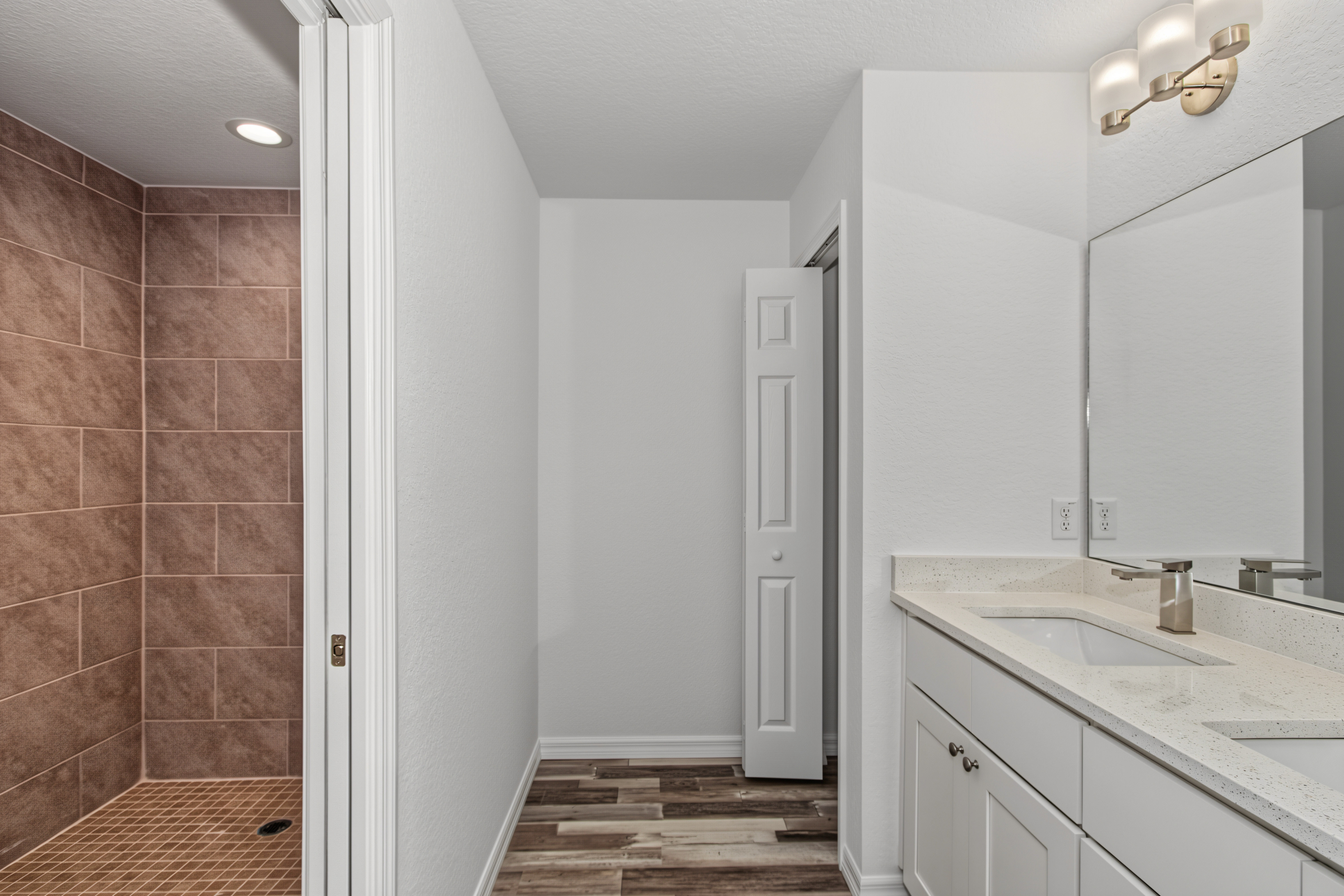 Primary bathroom vanity and mirror with adjacent view of walk-in tiled shower in Ocala, FL